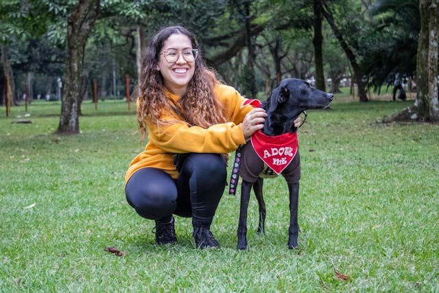 A smiling girl with her black dog during an outdoor activity.